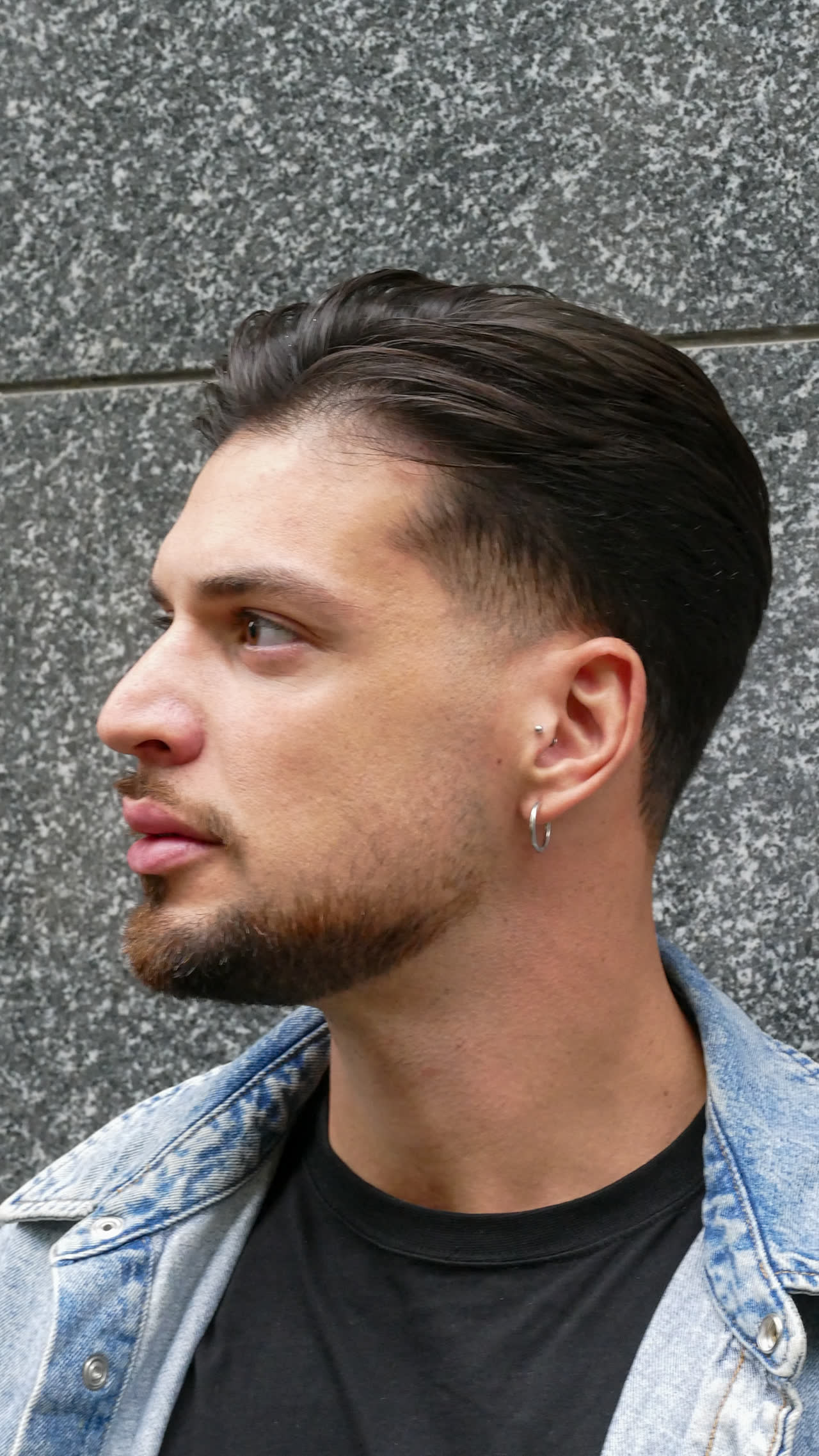 Capelli tirati indietro con sfumatura alta e barba corta definita